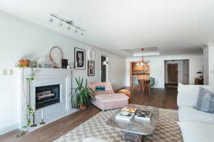 Living room featuring a tray ceiling, a tiled fireplace, ornamental molding, wood finished floors, and baseboards