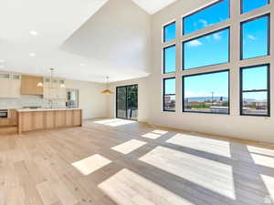 Living room with a vaulted ceiling, Picture window, recessed lighting and light hard wood floors