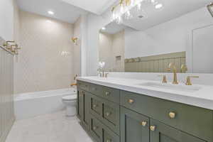 Full bathroom with double vanity, shower / washtub combination.