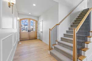 Foyer entrance featuring arched french doors, recessed lighting, light wood-type flooring, and stairs