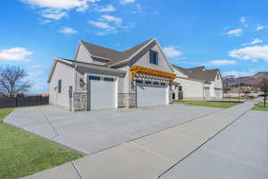 View of property exterior with a garage, a yard, stone siding, and concrete driveway