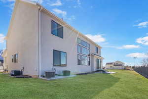 Rear view of property with a yard, fence, cooling unit.
