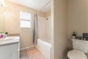 Full bathroom featuring shower / bath combo, vanity, toilet, and baseboards