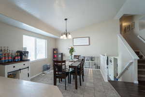 Dining area with baseboards, stairway, vaulted ceiling, and a notable chandelier