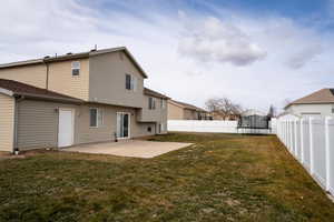 Rear view of house featuring a patio, a trampoline, a fenced backyard, and a lawn