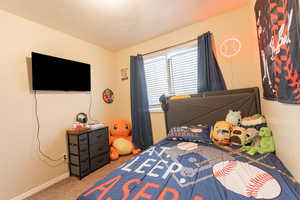 Carpeted bedroom with a textured ceiling and baseboards