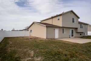 Rear view of house featuring a patio area, a fenced backyard, and a lawn