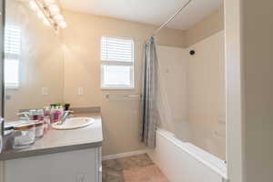 Full bathroom with shower / tub combo, baseboards, a notable chandelier, and vanity