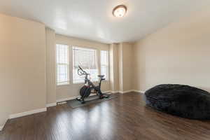 Workout room featuring visible vents, dark wood finished floors, and baseboards