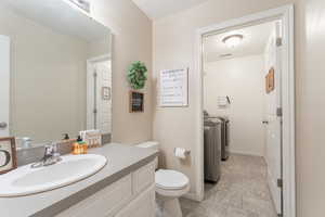 Bathroom with toilet, visible vents, vanity, baseboards, and independent washer and dryer