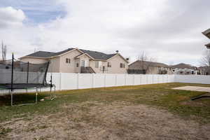 View of yard featuring a trampoline and fence