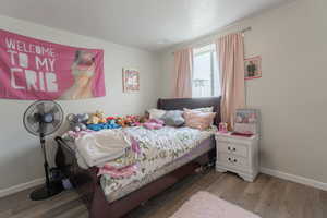 Bedroom featuring wood finished floors, visible vents, and baseboards