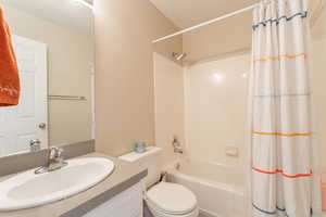 Full bathroom with toilet, shower / bath combo with shower curtain, and vanity