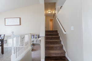 Stairs featuring vaulted ceiling and baseboards