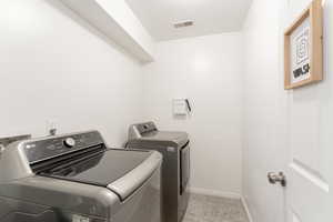 Washroom with laundry area, baseboards, visible vents, and separate washer and dryer