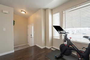 Exercise room with vaulted ceiling, baseboards, and wood finished floors