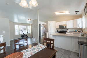 Dining room with vaulted ceiling, a textured ceiling, and baseboards