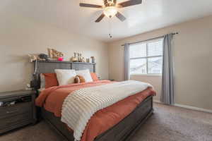 Carpeted bedroom featuring baseboards and a ceiling fan