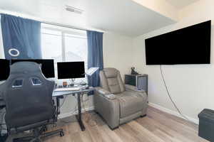 Office space with light wood-type flooring, visible vents, and baseboards