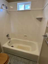 Full bathroom featuring tile patterned flooring and washtub / shower combination