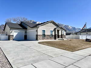 View of front of property with board and batten siding, fence, an attached garage, and a mountain view