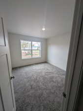 Empty room featuring baseboards and carpet flooring