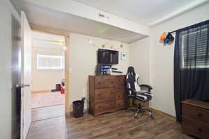 Office area featuring visible vents, baseboards, and wood finished floors
