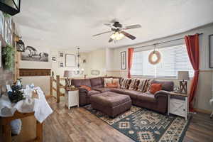 Living room with dark wood-style floors, baseboards, a textured ceiling, and ceiling fan with notable chandelier