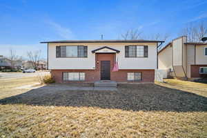 Bi-level home with brick siding and a front lawn