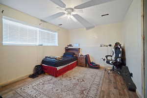 Bedroom with visible vents, ceiling fan, baseboards, and wood finished floors