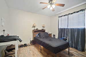 Bedroom featuring a textured ceiling, wood finished floors, and a ceiling fan