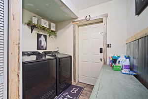 Washroom featuring laundry area, wood finished floors, and washing machine and clothes dryer