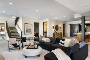 Living room featuring bar, stairway, light colored carpet, and recessed lighting