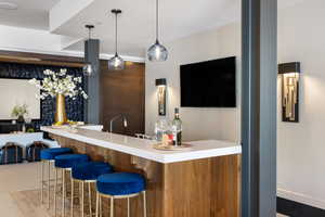 Bar featuring decorative light fixtures and wet bar