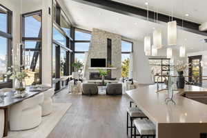 Interior space featuring a center island with sink, wood-type flooring, open floor plan, decorative light fixtures, and a stone fireplace