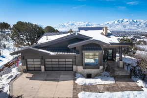 View of front of property featuring a garage, concrete driveway, a standing seam roof, and a mountain view