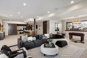 Living area featuring a dry bar, baseboards, light colored carpet, an inviting chandelier, and recessed lighting