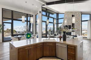 Kitchen with open floor plan, light countertops, stainless steel dishwasher, a mountain view, and a sink