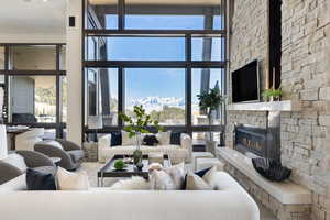 Living area with plenty of natural light, a high ceiling, and a stone fireplace