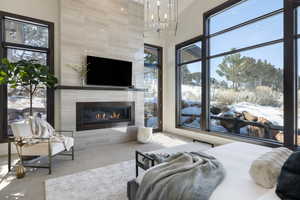 Carpeted bedroom with a towering ceiling, an inviting chandelier, and a premium fireplace