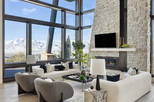 Living area with light wood-type flooring, a fireplace, a mountain view, and a towering ceiling