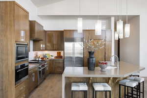 Kitchen with a kitchen island with sink, modern cabinets, and built in appliances