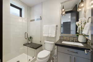 Full bathroom with a shower stall, backsplash, toilet, and vanity