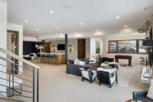 Living room featuring a chandelier, bar, light carpet, and recessed lighting