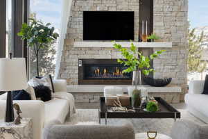 Living room with a stone fireplace and wood finished floors