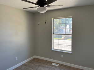 Bedroom featuring dark wood-style floors, visible vents, ceiling fan, a textured ceiling, and baseboards