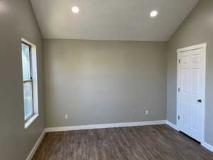 Bedroom with a healthy amount of sunlight, vaulted ceiling, and dark wood finished floors