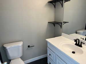 Bathroom featuring toilet, baseboards, and vanity