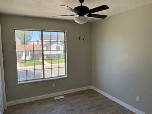 Bedroom with a textured ceiling, ceiling fan, dark wood-type flooring, visible vents, and baseboards