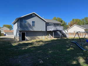 Back of house with stairs, fence, a deck, a yard, and a playground